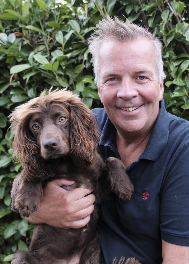 Profile shot On the left is a brown cocker-spaniel, Bear, being held by the company Director and Coach, Kim Churchill